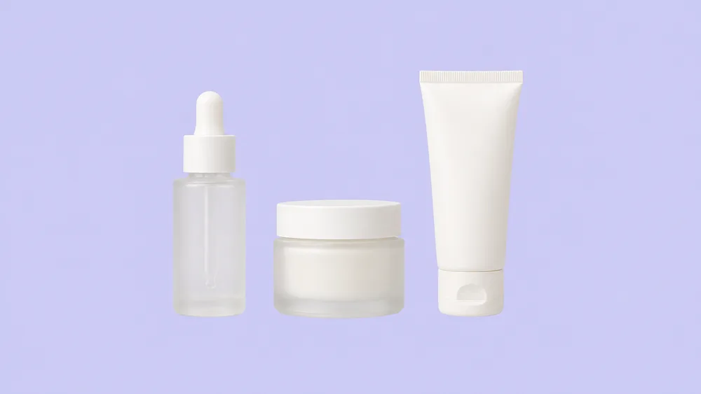 Serum dropper bottle, cream jar and tube from a natural skin care line on a lavender background